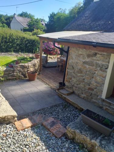 une arrière-cour avec une terrasse en bois et un bâtiment en pierre dans l'établissement LA PETITE MAISON DU SABOT, à Langonnet