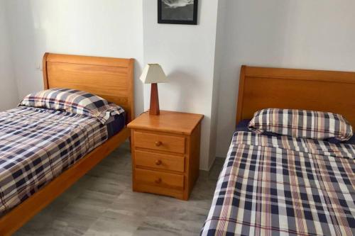 - une chambre avec 2 lits et une table de nuit avec une lampe dans l'établissement Eclipse de mar: Cozy Beach Home, Costa de la Luz, à Cadix