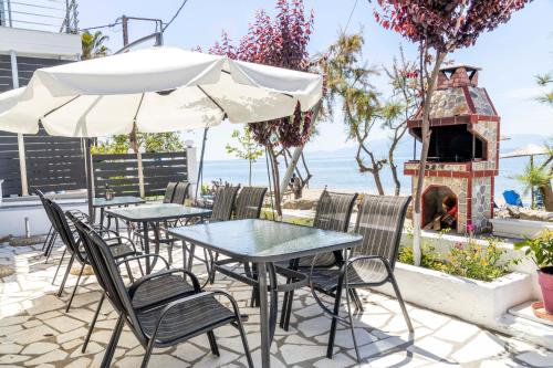 a patio with tables and chairs and a pizza oven at Dimitra Beach Apartments - Nea Karvali Kavala in Néa Karváli