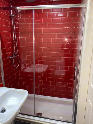 a red tiled bathroom with a shower and a sink at Cathedral Hotels Norwich in Norwich