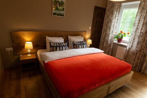 a bedroom with a large red bed with a window at Hotel Benevilla in Alūksne