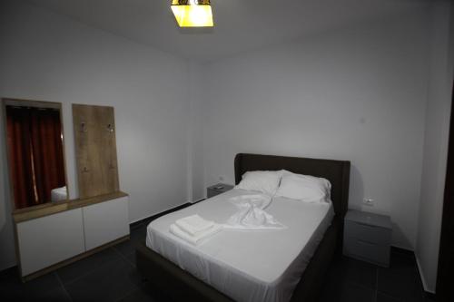 a bedroom with a white bed with a night stand at Deda Apartments in Sarandë