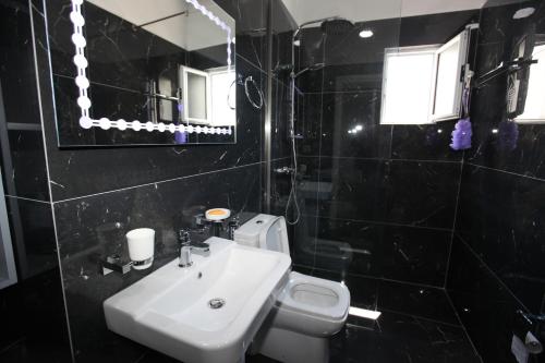 a bathroom with a sink and a toilet and a mirror at Deda Apartments in Sarandë