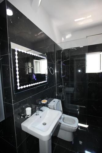 a bathroom with a sink and a toilet and a mirror at Deda Apartments in Sarandë