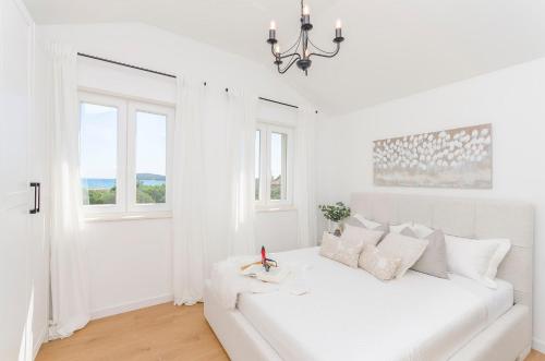 a white living room with a white couch and windows at Sunset horizon in Krapanj