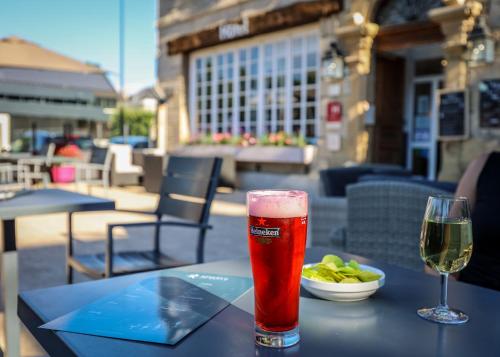 un verre de bière et une assiette de nourriture sur une table dans l'établissement Hôtel La Réserve de Brive, à Brive-la-Gaillarde