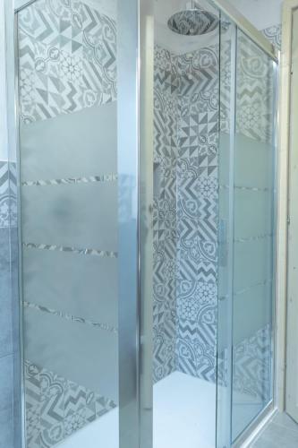 a shower with a glass door with a patterned wall at Martalagattahome in San Felice del Benaco