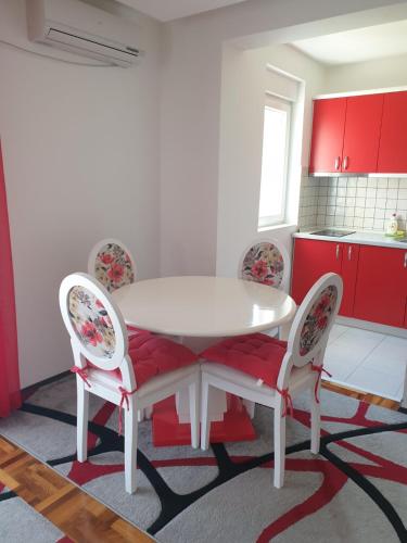 a white table and chairs in a kitchen with red cabinets at Lux Apartman Ristić 2 in Soko Banja