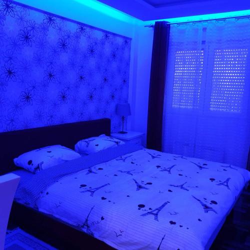 a bedroom with a bed with a blue light at Lux Apartman Ristić 2 in Soko Banja