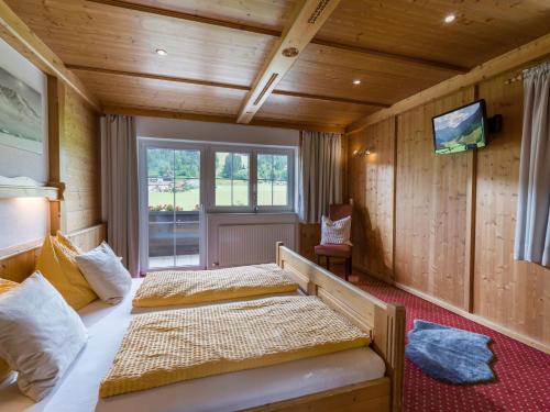 two beds in a room with wooden walls and a tv at Appartement Felsenheim in Westendorf