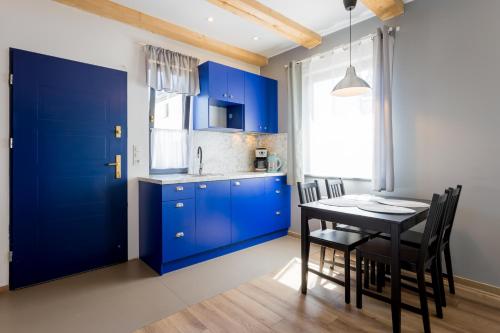 a kitchen with blue cabinets and a table with chairs at Domki Łeba, Apartamenty Łeba - Polanki23 - basen, sauna, kino in Łeba