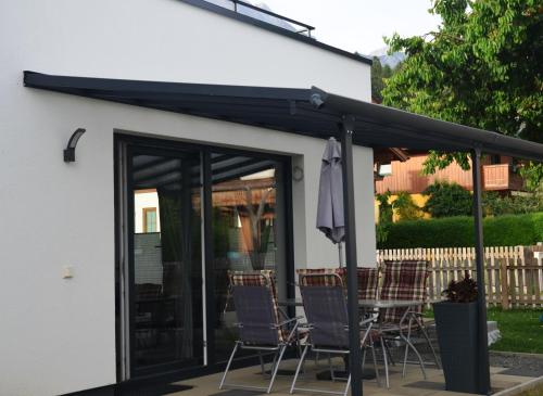 a patio with a black awning and chairs at Appartement HANNE in Saalfelden am Steinernen Meer