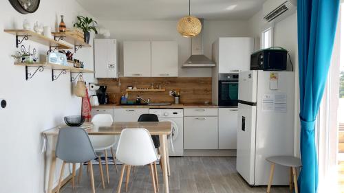 uma cozinha com armários brancos e uma mesa e cadeiras em Superbe studio, vue lac, Spirou, rando, velo em Monteux