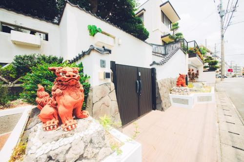 une statue d'un chat assis sur un rocher devant un bâtiment dans l'établissement クリスタルヴィラ金城, à Naha