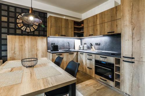 a kitchen with wooden cabinets and a wooden table at Aparthotel Klínovec Views in Loučná pod Klínovcem