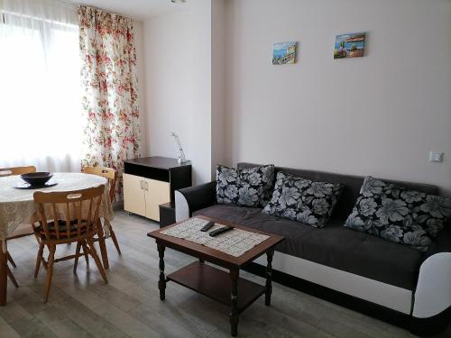 a living room with a black couch and a table at White home-apartament in Burgas City