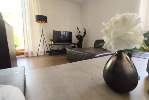 un jarrón con flores blancas sobre una mesa en la sala de estar en Apartman Panorama Park & Free Parking, en Žilina