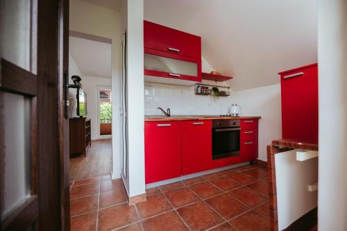 a red kitchen with red cabinets and a tile floor at Apartment Oddih in Bled