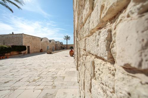 a stone alley with a building and a palm tree at Masseria Francescani in Torre Chianca