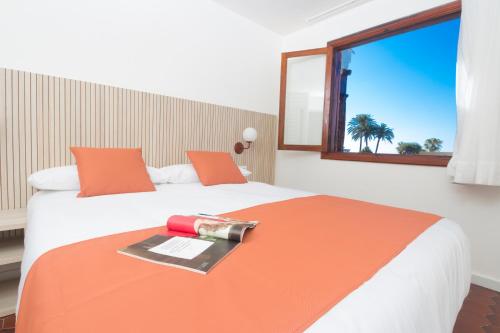 1 dormitorio con 1 cama con manta naranja y ventana en Alsol Las Orquídeas, en Playa del Inglés