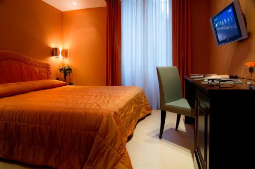 a hotel room with a bed and a desk and a television at Marcella Royal Hotel - Rooftop Garden in Rome