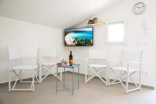 a room with white chairs and a table with a bottle of wine at Appartamento Limone in Splendida villa Nature al mare di Scopello Zingaro in Scopello