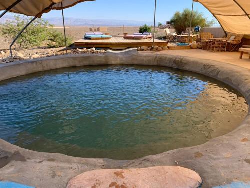 una piscina d'acqua con tavolo e ombrellone di Desert Days mud cabin's Resort a Zuqim