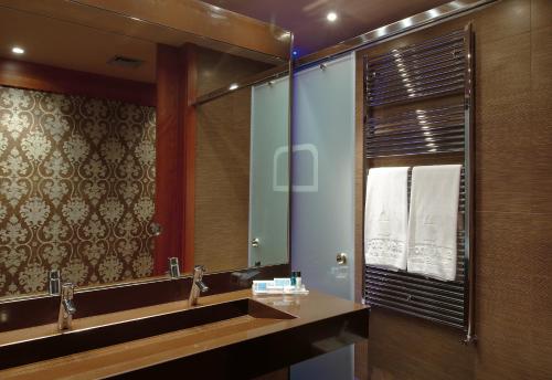 a bathroom with a large mirror and a sink at Balneario Font Vella- Adults Only in Sant Hilari Sacalm