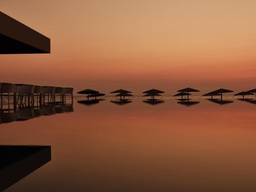 a group of umbrellas in the water at sunset at Caravel Suites - Adults Only in Tsilivi