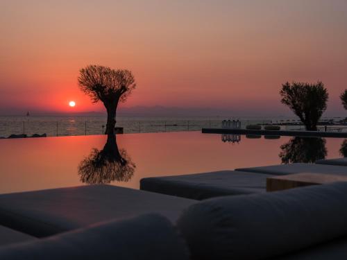 a swimming pool with a sunset in the background at Caravel Suites - Adults Only in Tsilivi