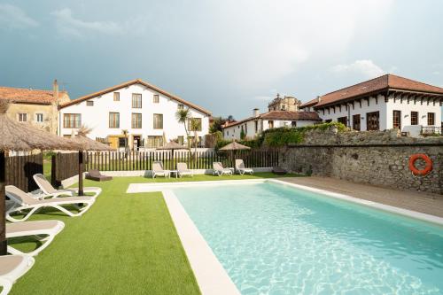 a swimming pool with chairs and a house at Jardines Villaverde in Villaverde de Pontones