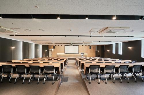 a conference room with tables and chairs and a screen at Eden Paradise Hotel in Icheon