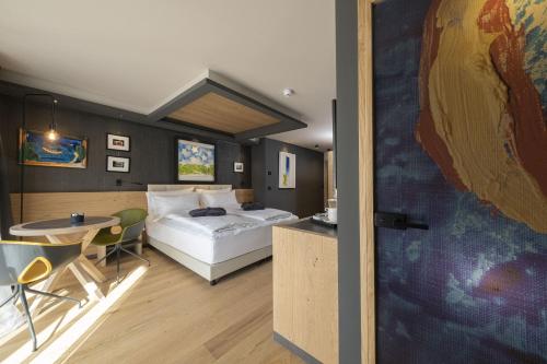 a hotel room with a bed and a table and a tableablish at Locanda degli Artisti Art Hotel in Canazei