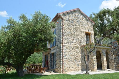 an old stone house with a table and a tree at Casolare Cento Ulivi Luxury & Charme in Ascea