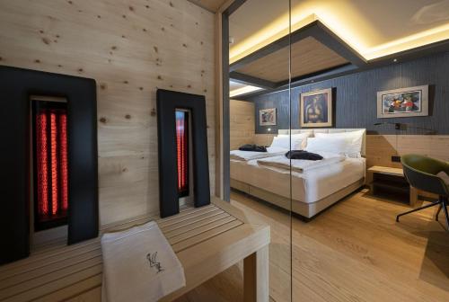 a bedroom with a bed and a glass wall at Locanda degli Artisti Art Hotel in Canazei