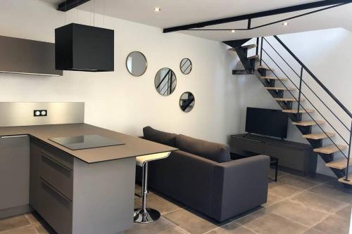 a kitchen with a couch and a table and a staircase at Les chambres Berguoises Duplex calme au coeur de Bergues in Bergues