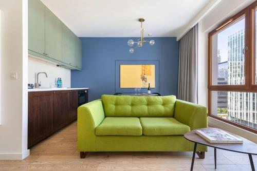 eine grüne Couch in einer Küche mit blauer Wand in der Unterkunft Rent like home - Karolkowa 28 II in Warschau