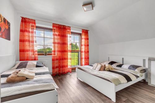 two beds in a bedroom with red curtains at Rezidence Rokytnice in Rokytnice nad Jizerou