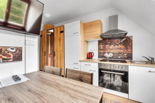 a kitchen with a wooden table and a stove at Rezidence Rokytnice in Rokytnice nad Jizerou