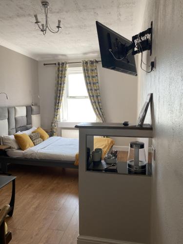 a room with a bed and a desk with a television at Astral Lodge in Hastings