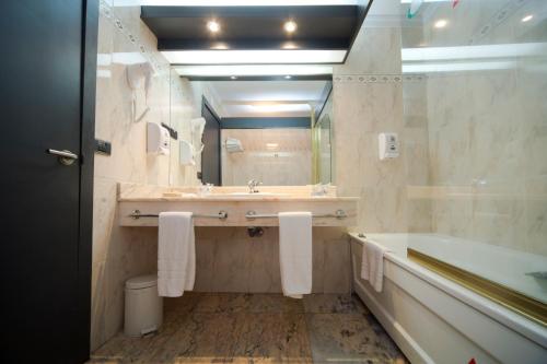 a bathroom with a sink and a tub and a mirror at Hotel Bahía de Vigo in Vigo