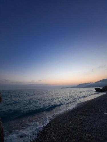 a beach with the sun setting over the water at Albert Guest House in Borsh