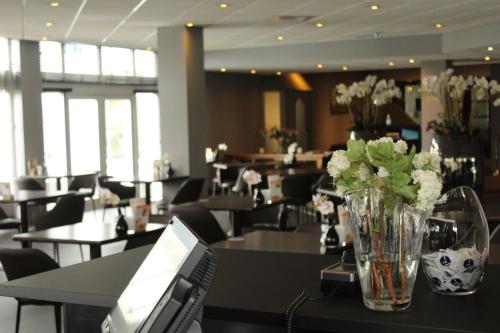 a dining room with a table with a vase of flowers at Fletcher Hotel-Restaurant ‘s-Hertogenbosch in Den Bosch