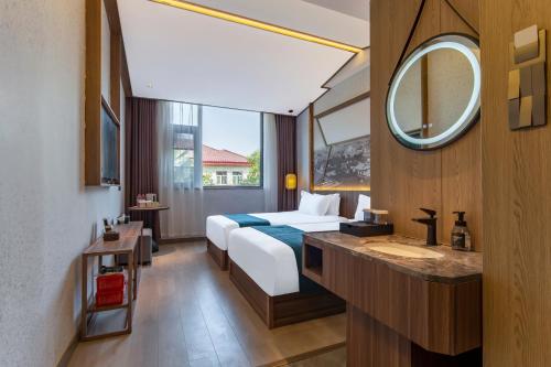 a hotel room with a bed and a sink and a mirror at 洛阳Travel World Hotel in Luoyang