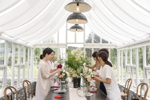 a group of women standing around a table in a white tent at Eden Paradise Hotel in Icheon