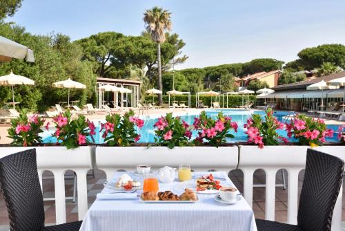 einen Tisch mit Essen darauf neben einem Pool in der Unterkunft Park Hotel Marinetta - Beach & Spa in Marina di Bibbona