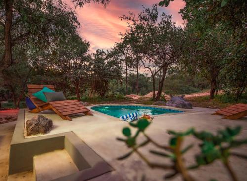 um quintal com uma piscina e duas cadeiras em Jackals Dream - Self Catering Villa bordering Kruger National Park em Marloth Park