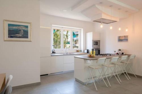een keuken met witte kasten en een eiland met barkrukken bij WHITE HOUSE SORRENTO - CASA VACANZA in Sorrento