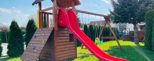 a playground with a red slide in a yard at Meggyes Hotel in Szerencs