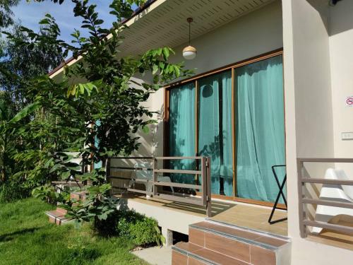 a house with a balcony with blue curtains at Morinaka Craftfe & Poshtel in Ban Na Muang